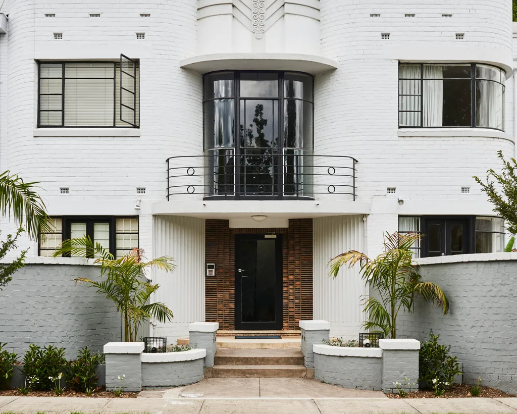Art Deco style house with white facade and black accents under a blue sky.
