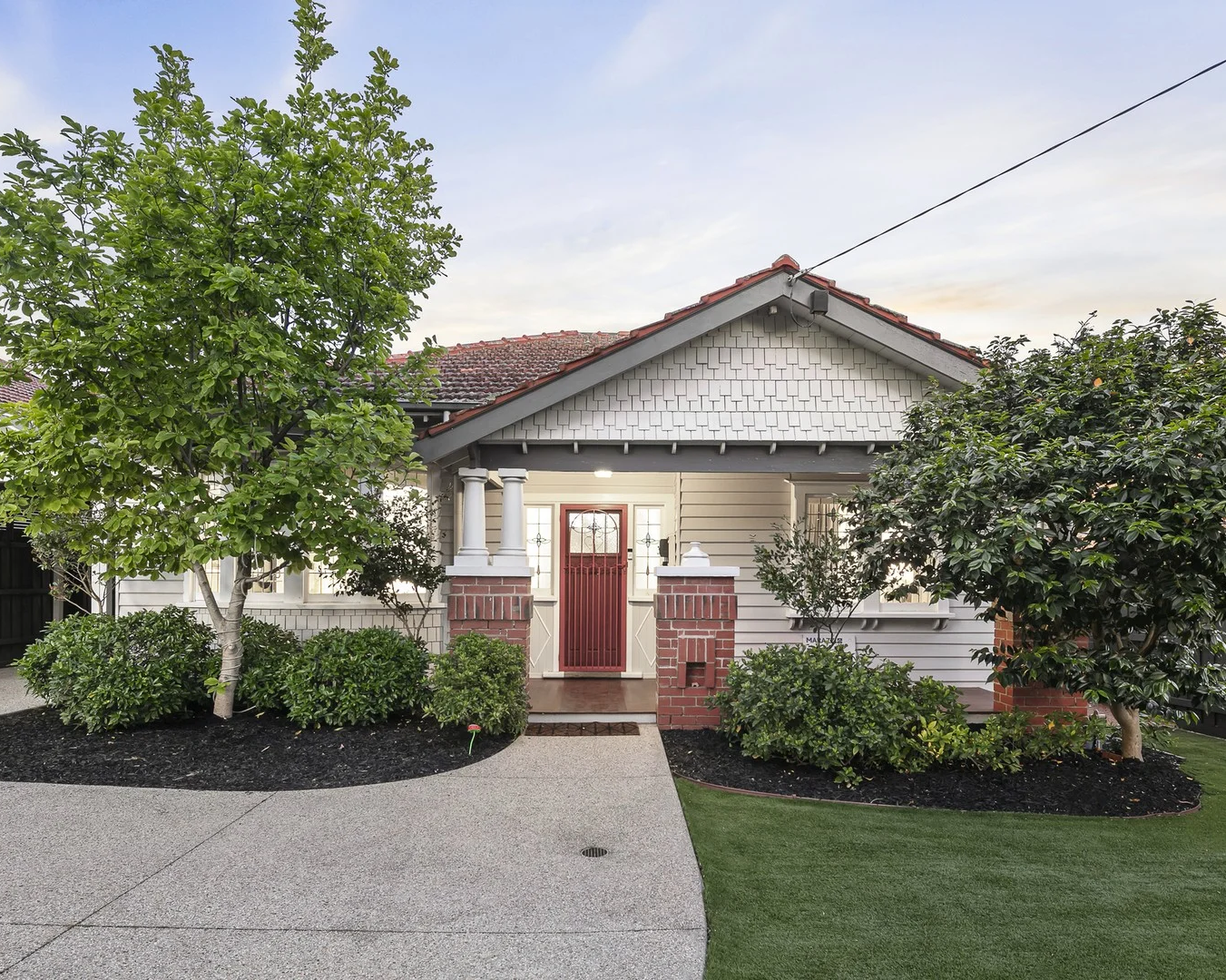 House with a red door and greenery in front on a clear day