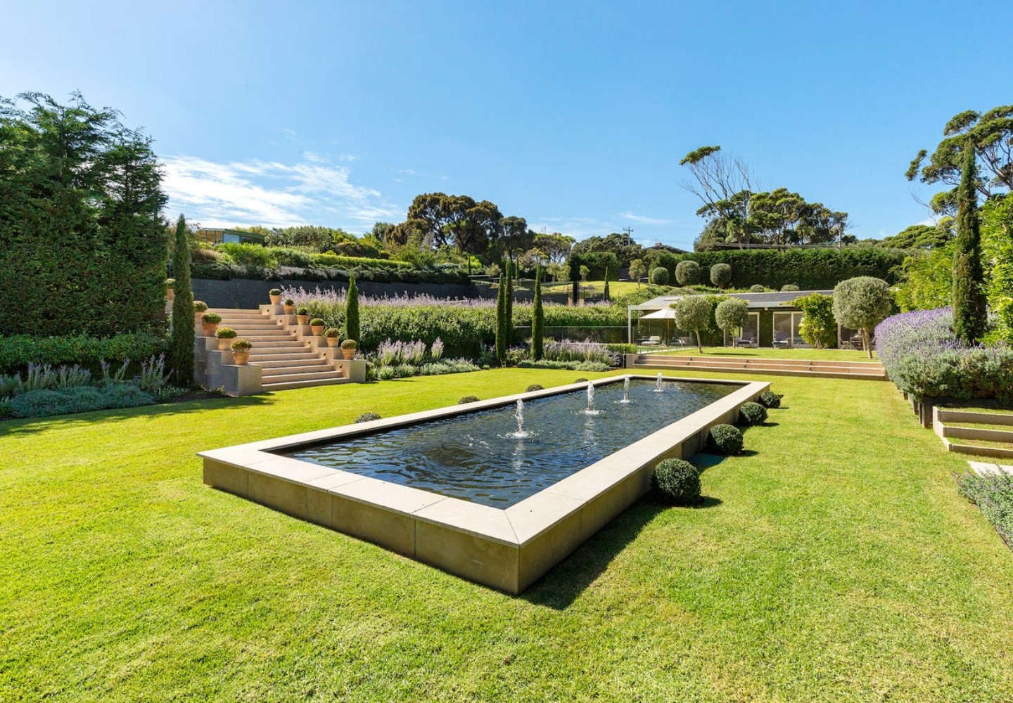 Garden with a rectangular pool and greenery under a clear blue sky