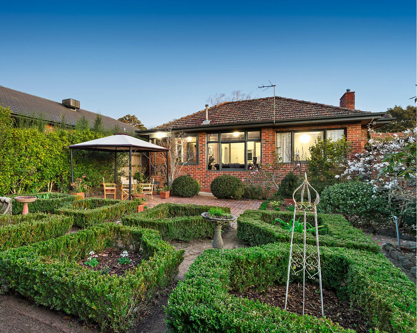 Garden with geometric hedges and a house in the background