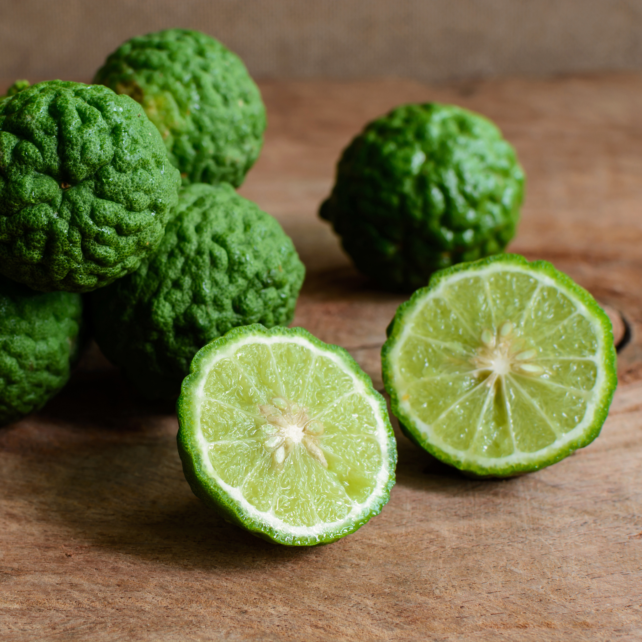 Dwarf Kaffir Lime on a wooden surface with one cut in half